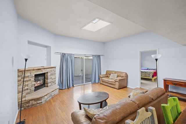 living room featuring a fireplace, a skylight, and hardwood / wood-style floors