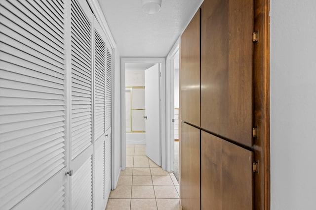 corridor with a textured ceiling and light tile patterned floors