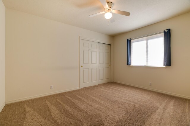 unfurnished bedroom with ceiling fan, a closet, carpet flooring, and baseboards