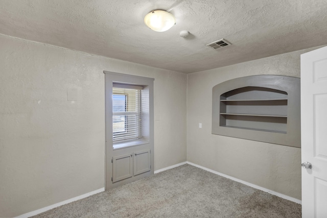 empty room featuring a textured ceiling and light colored carpet