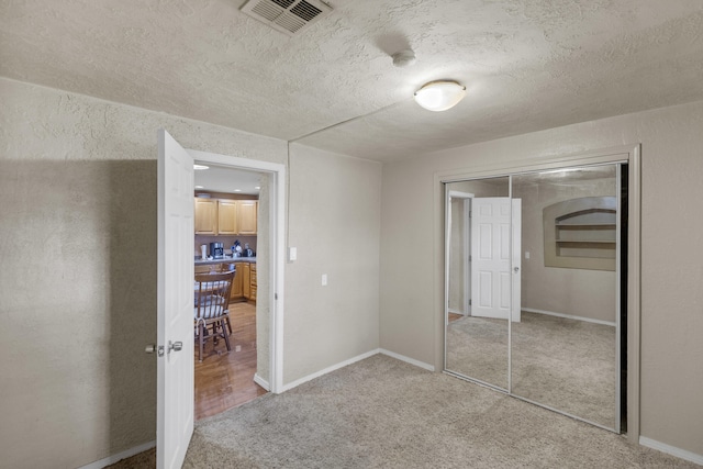 unfurnished bedroom with carpet, a textured ceiling, and a closet