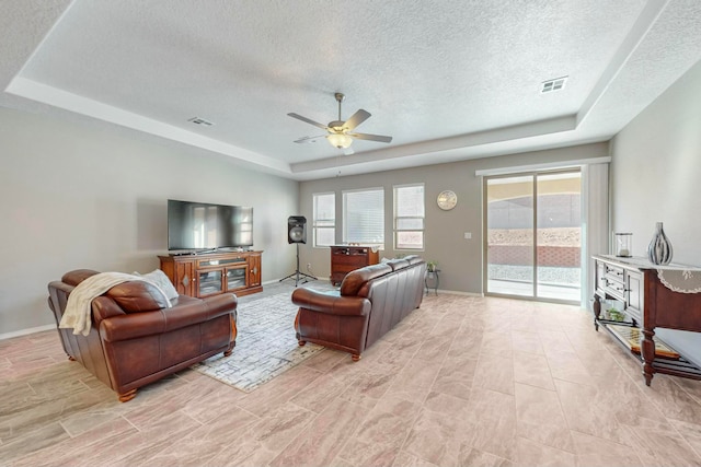 living room featuring a textured ceiling, a raised ceiling, and ceiling fan