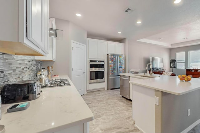 kitchen featuring decorative backsplash, stainless steel appliances, a kitchen island with sink, sink, and white cabinets