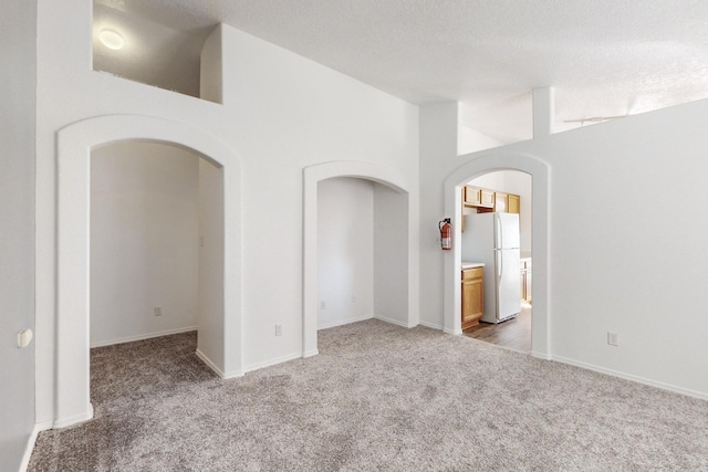 spare room with carpet flooring, lofted ceiling, and a textured ceiling