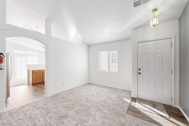 carpeted foyer with lofted ceiling and a textured ceiling