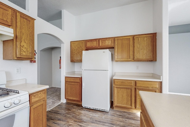 kitchen with stove, white fridge, and dark wood-type flooring