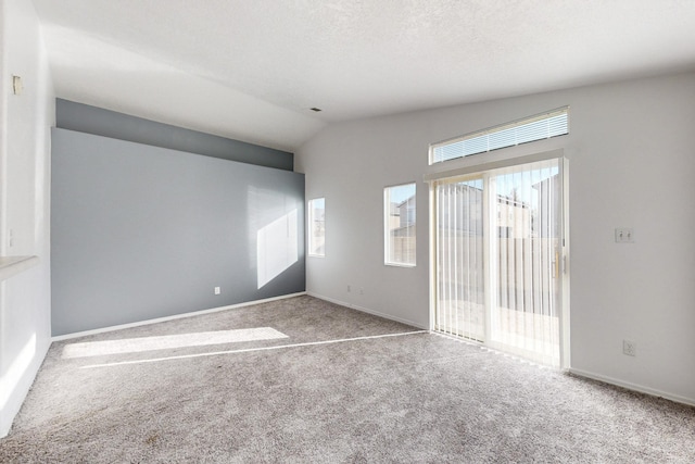 spare room with carpet floors, a textured ceiling, and vaulted ceiling