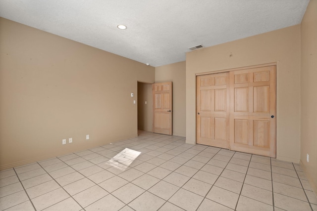 unfurnished bedroom featuring a closet, light tile patterned flooring, and a textured ceiling