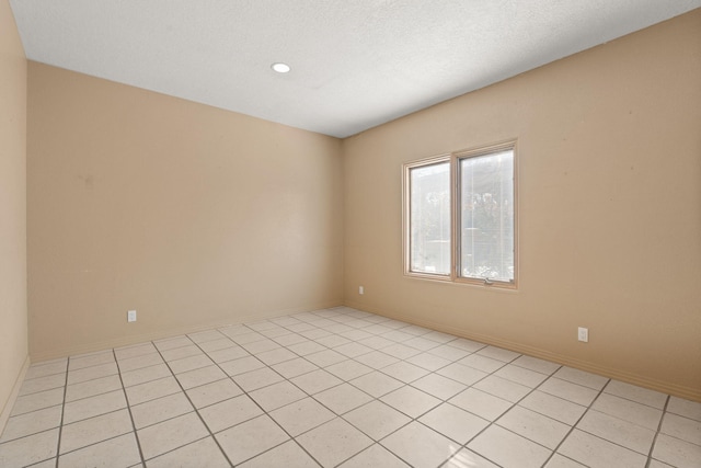 tiled empty room with a textured ceiling