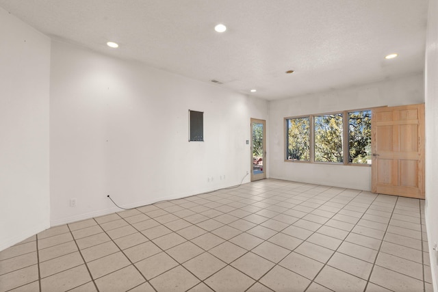 tiled empty room featuring a textured ceiling