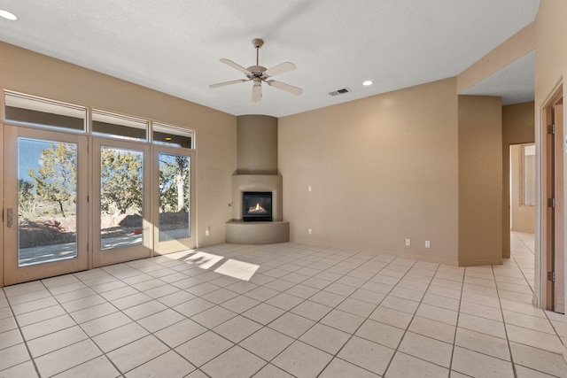 unfurnished living room featuring light tile patterned floors, a large fireplace, a textured ceiling, and ceiling fan