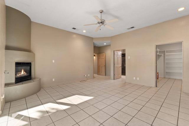 unfurnished living room with light tile patterned floors, a large fireplace, and ceiling fan