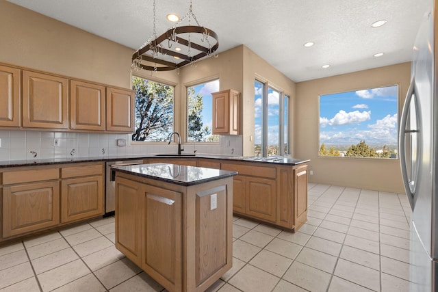 kitchen with a center island, sink, backsplash, a textured ceiling, and appliances with stainless steel finishes