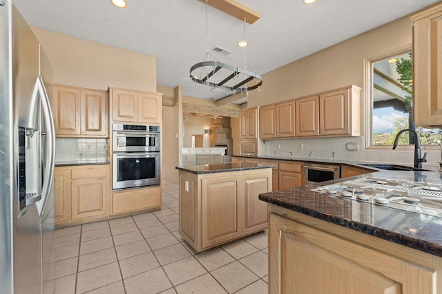 kitchen with hanging light fixtures, a center island, stainless steel appliances, and light brown cabinetry