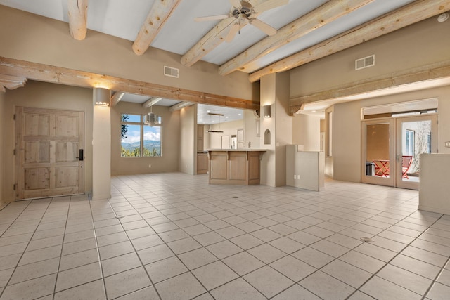 unfurnished living room with beamed ceiling, ceiling fan, and light tile patterned flooring