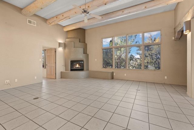 unfurnished living room with beam ceiling, ceiling fan, and light tile patterned floors