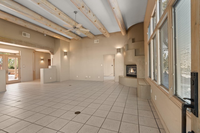 unfurnished living room with beamed ceiling, ceiling fan, light tile patterned flooring, and a fireplace