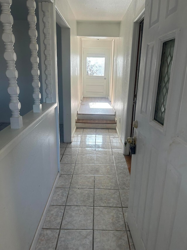 hallway with light tile patterned flooring and a textured ceiling