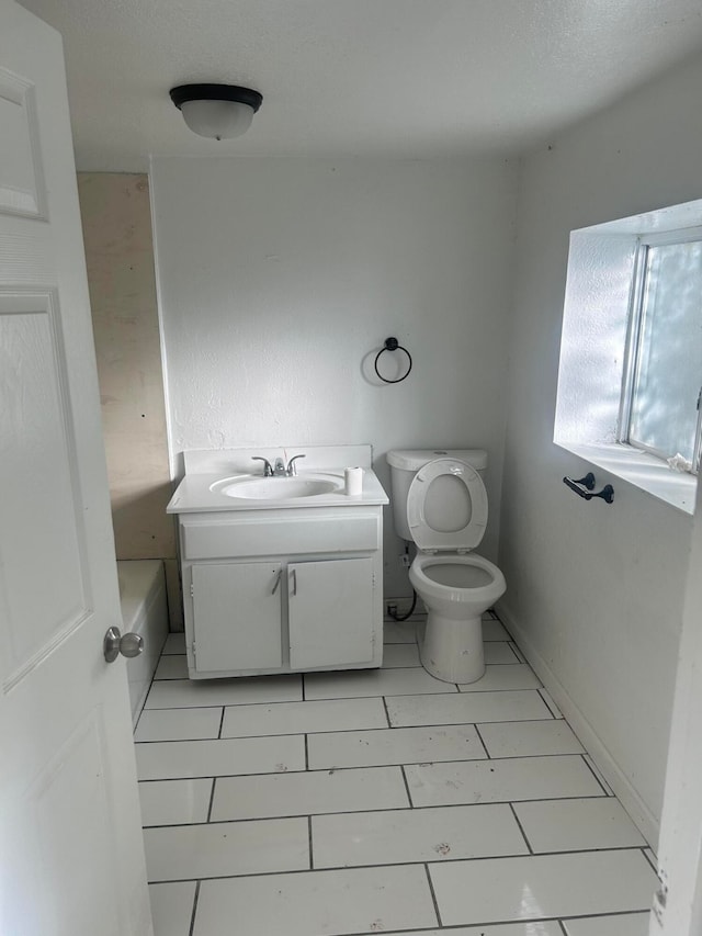 bathroom featuring a bathing tub, vanity, toilet, and tile patterned flooring