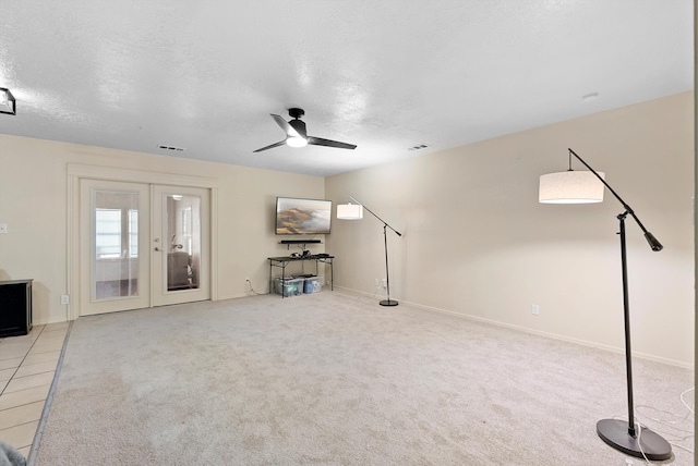 unfurnished living room featuring ceiling fan, light colored carpet, a textured ceiling, and french doors