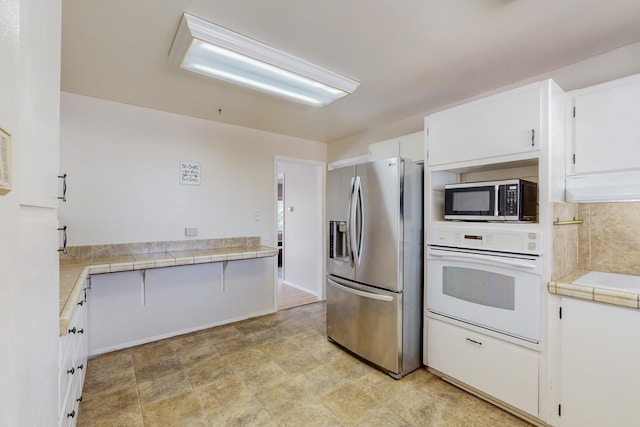 kitchen with white cabinetry, appliances with stainless steel finishes, and tile countertops