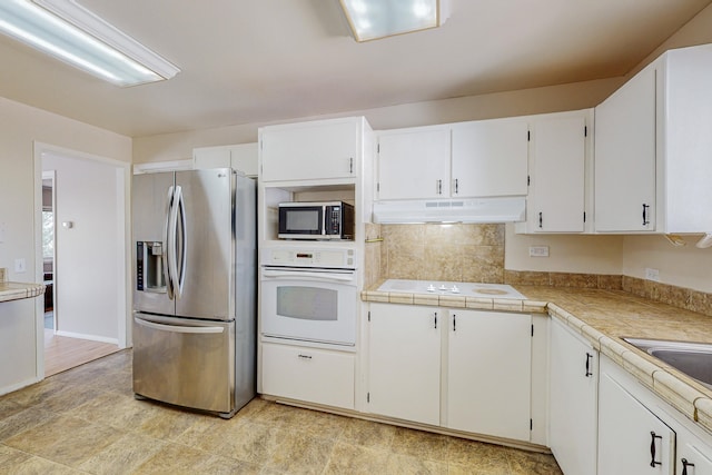 kitchen with sink, white cabinetry, tile countertops, stainless steel appliances, and decorative backsplash