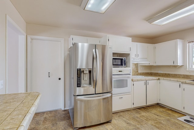 kitchen featuring stainless steel appliances, white cabinetry, and tile counters