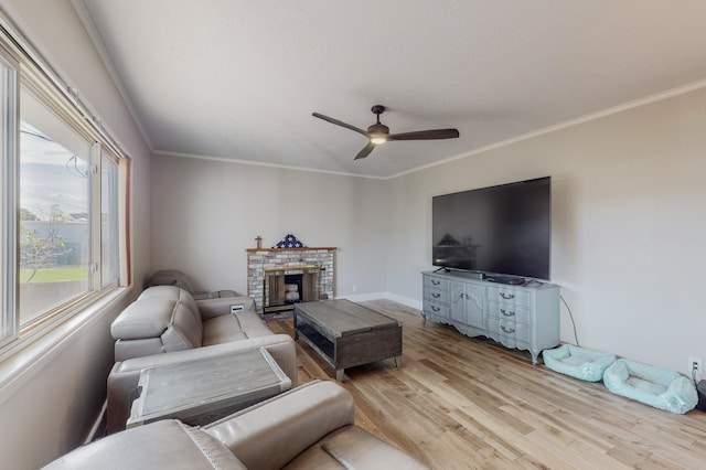 living room with ornamental molding, ceiling fan, a fireplace, and light wood-type flooring