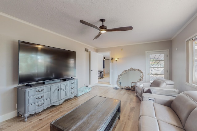 living room with ornamental molding, ceiling fan, a textured ceiling, and light wood-type flooring