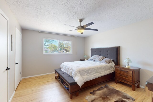 bedroom with a textured ceiling, light hardwood / wood-style floors, and ceiling fan