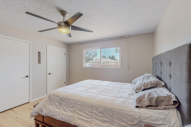 bedroom with a textured ceiling, ceiling fan, and light wood-type flooring