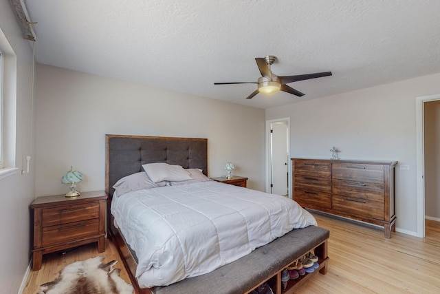 bedroom with a textured ceiling, ceiling fan, and light hardwood / wood-style flooring