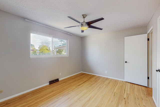 empty room with ceiling fan, a textured ceiling, and light wood-type flooring