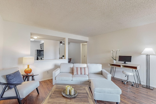 living room featuring ceiling fan, wood-type flooring, and a textured ceiling