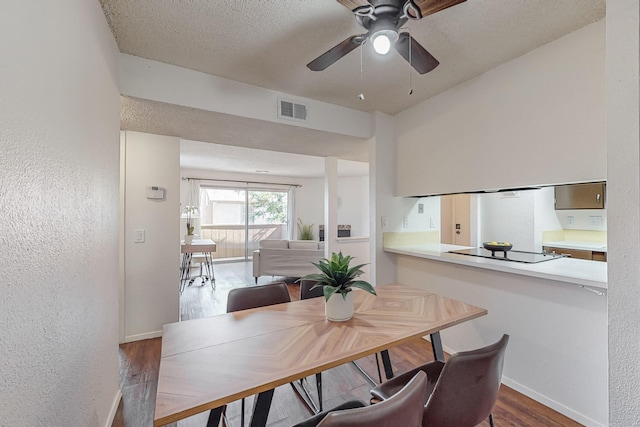 dining room featuring hardwood / wood-style flooring, ceiling fan, and a textured ceiling