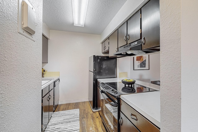 kitchen with dishwasher, black refrigerator, range with electric stovetop, light hardwood / wood-style floors, and a textured ceiling