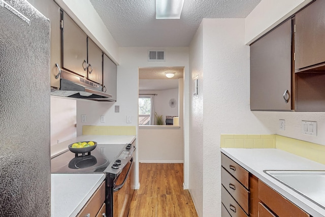 kitchen with sink, a textured ceiling, stainless steel range with electric cooktop, and light hardwood / wood-style flooring