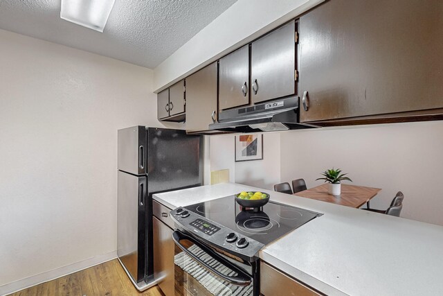 kitchen featuring black fridge, a textured ceiling, electric range oven, and light hardwood / wood-style flooring