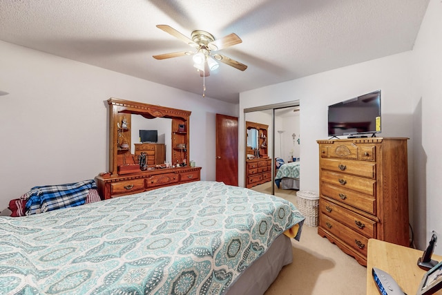 bedroom with a textured ceiling, ceiling fan, light carpet, and a closet