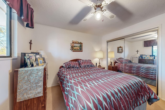 carpeted bedroom featuring ceiling fan, a textured ceiling, and a closet