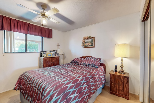 bedroom featuring ceiling fan, light colored carpet, and a textured ceiling