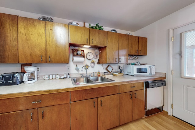 kitchen with light wood-type flooring, white appliances, and sink