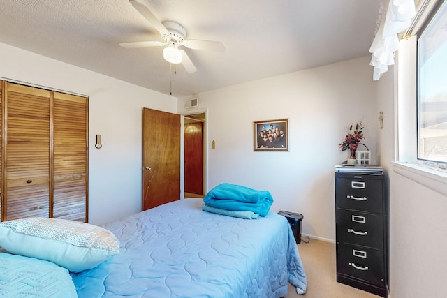 bedroom with multiple windows, ceiling fan, a closet, and light colored carpet