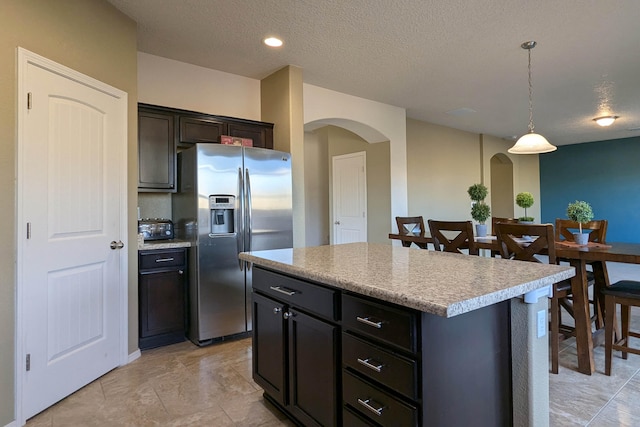 kitchen featuring stainless steel fridge with ice dispenser, a center island, pendant lighting, and a textured ceiling