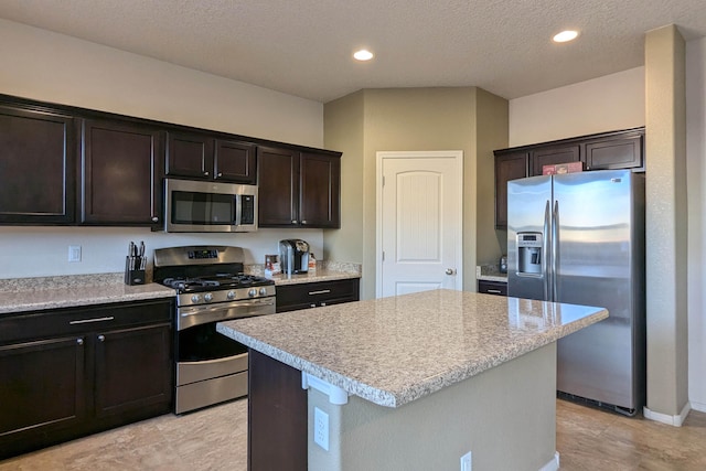 kitchen featuring dark brown cabinets, a textured ceiling, stainless steel appliances, and a kitchen island