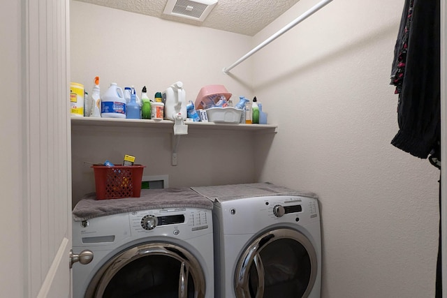 clothes washing area with washer and clothes dryer and a textured ceiling