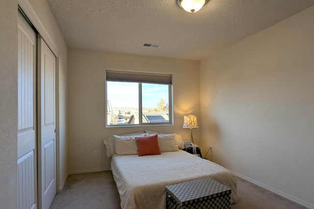 bedroom featuring light carpet, a closet, and a textured ceiling