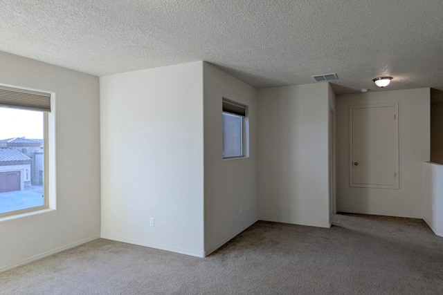 carpeted empty room featuring a textured ceiling