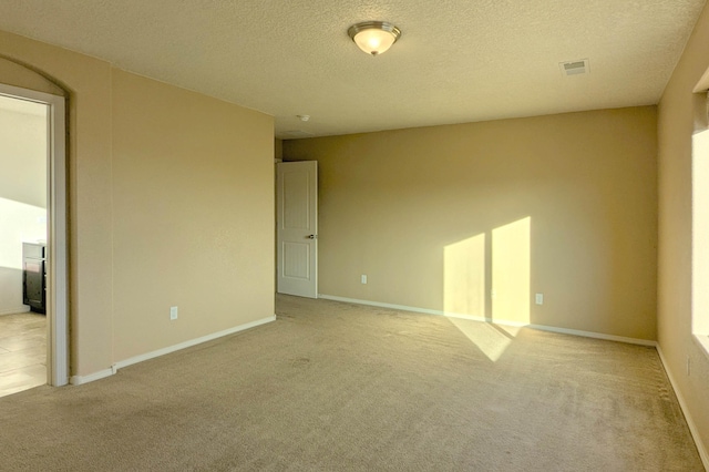 carpeted empty room featuring a textured ceiling