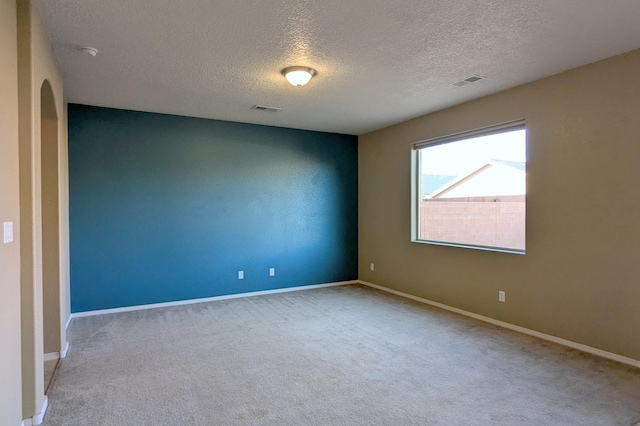 empty room with light colored carpet and a textured ceiling